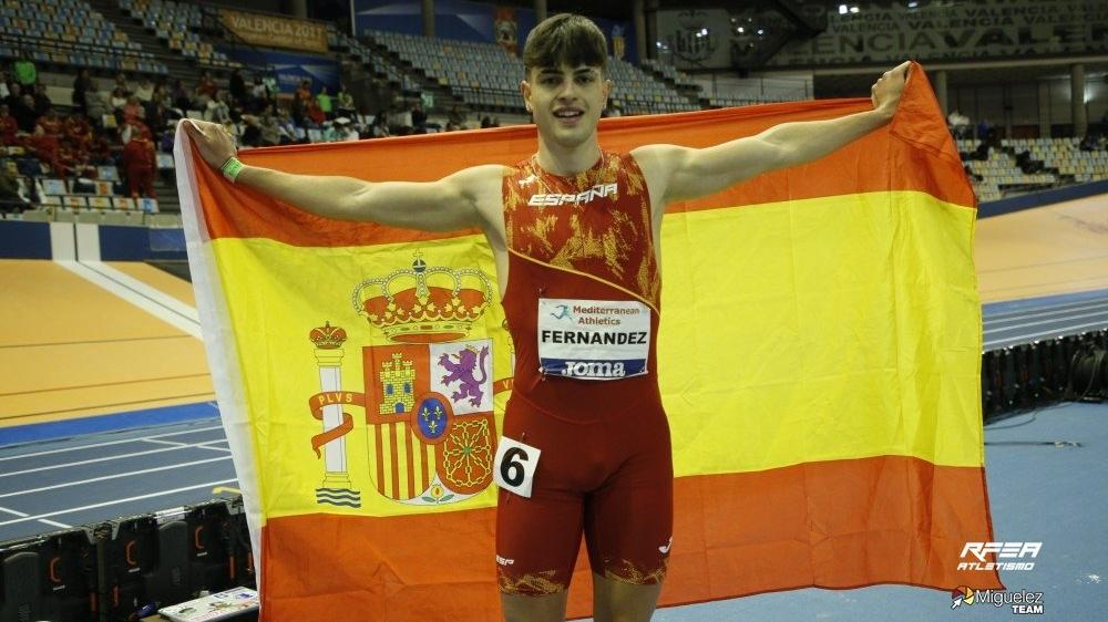 Markel Fernández celebrando con la bandera de España su victoria en el Campeonato del Mediterráneo Sub-23 de atletismo en pista cubierta, Valencia 2023.